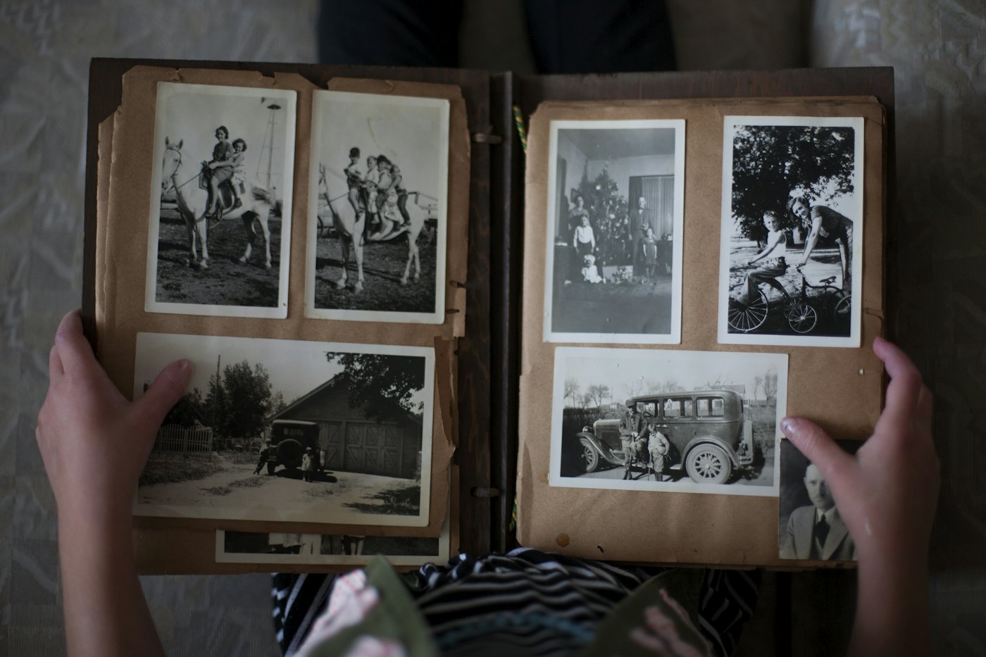 Hände halten ein geöffnetes Fotoalbum mit alten Schwarz-Weiß-Familienbildern.
